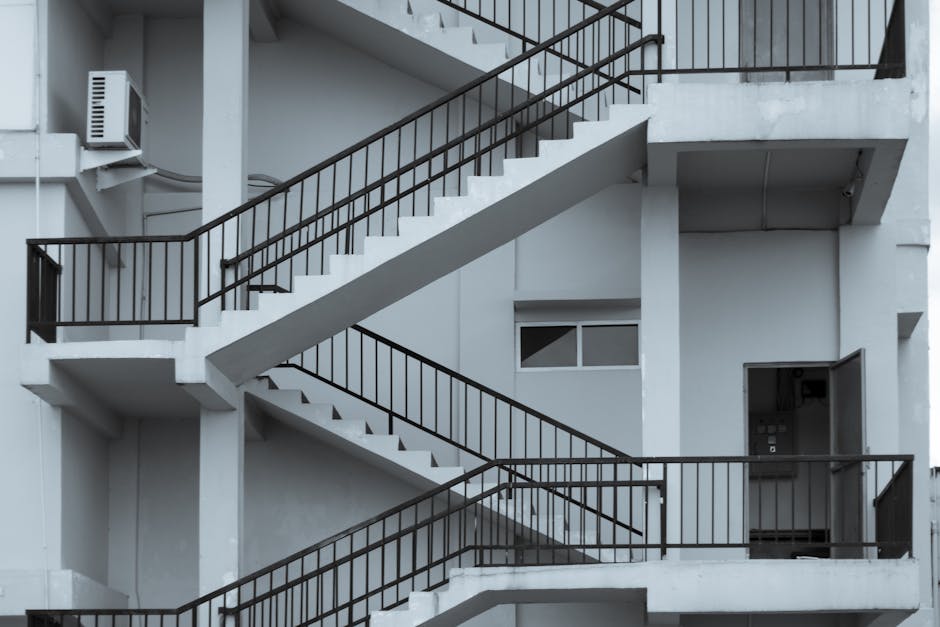 A set of steep, yellow and black striped industrial stairs with metal handrails on both sides, leading up inside a multi-level facility or warehouse. The steps are made of durable material, with some
